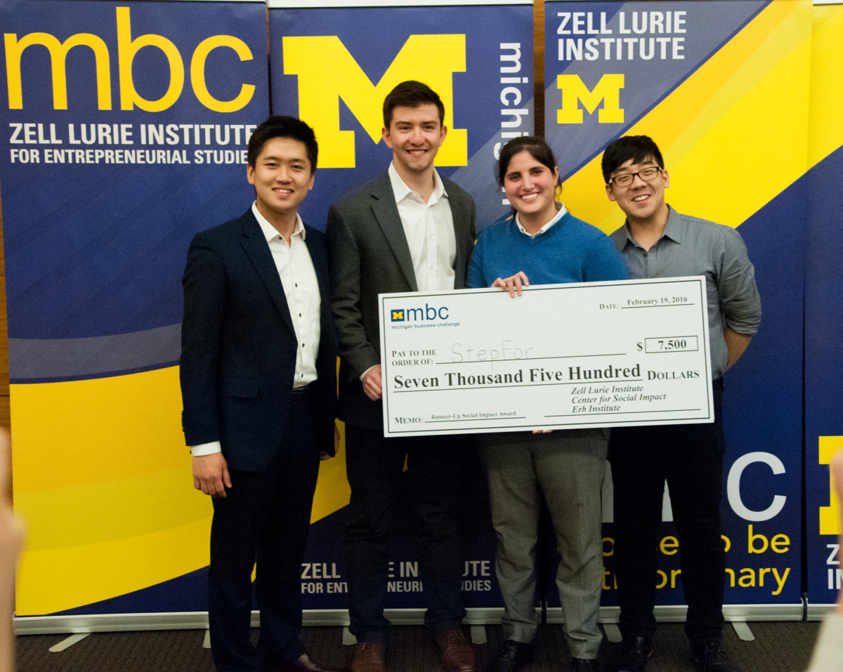 Four smiling MBC contestants holding large check that reads, "Pay to the order of: StepFor, $7,500 Seven Thousand Five Hundred Dollars, Zell Lurie Institute, Center for Social Impact, Erb Institute."